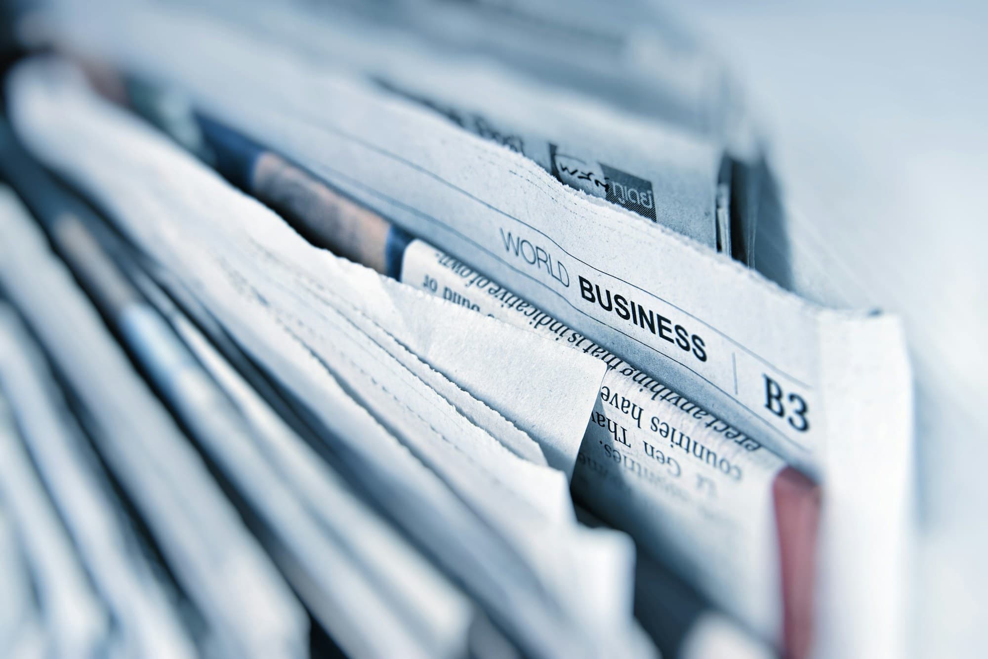 A newspaper and a laptop on a desk